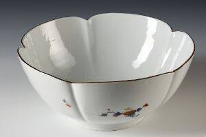  An elegant white porcelain bowl with scalloped edges featuring a small, painted scene of figures in classic dress on one side, set against a light gray background.