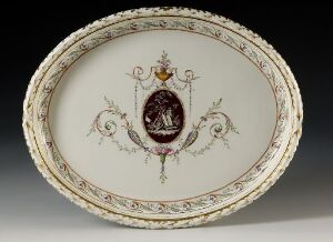  An oval-shaped porcelain platter with an ornate green, gold, and burgundy leafy border design, featuring a central coat of arms with a classical scene on a burgundy background, all set against a neutral gray backdrop.