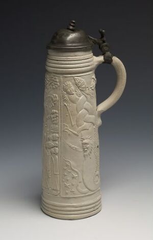  A cylindrical stoneware beer stein titled "Kristus jager djevelen" with a muted ecru body featuring high relief decoration and a pewter lid. The stein showcases scenes in relief, suggestive of a narrative and is set against a dark background, emphasizing the craftsmanship and the contrasting materials. Artist is unknown.