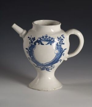  A white ceramic jug with intricate cobalt blue floral designs, featuring a large handle and a spout, set against a grey background. Artist name and title are unknown.