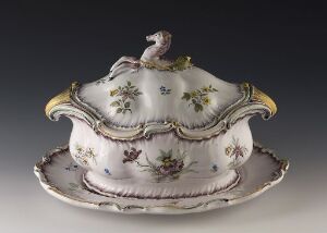  An elegant, antique porcelain tureen with gold trim and floral designs on a matching tray, set against a soft gray background.