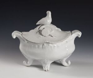  A glossy white porcelain tureen with ornate handles and a lid topped with a bird-shaped finial, set against a soft grey background.