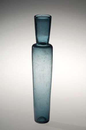  A minimalist, slender tall glass vase in a pale teal color with a frosted base and a more transparent neck, set against a gradient background fading from light to dark. Artist name and title are unknown.