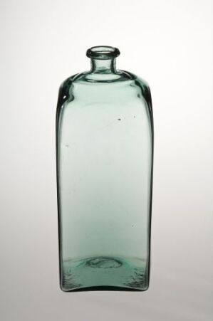  An antique aquamarine glass bottle with a narrow neck and rounded shoulders stands against a plain gradient background, showcasing the bottle's hand-blown imperfections and the soothing color of the glass.