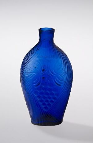  A cobalt blue glass vase with a narrow neck and intricate textured patterns reminiscent of fish scales, displayed against an off-white background.