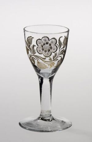  A clear glass goblet with a decorative floral etching, standing against a neutral backdrop.