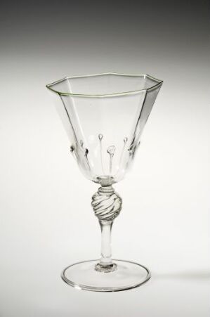  A clear glass goblet with a hexagonal bowl, a twisted stem, and a flat, circular foot, set against a soft grayish-white background.