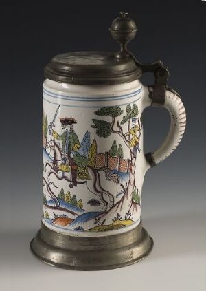  A traditional hand-painted ceramic beer stein with a pewter lid, featuring a colorful landscape scene with hills, a river, trees, and a village, finished with a sturdy handle and decorative metallic lid.