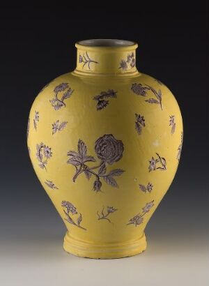  Traditional ceramic vase with a bright yellow base color, featuring intricate dark purplish-brown floral patterns and insect motifs, displayed against a dark gradient background.