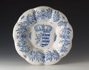  Vintage blue and white ceramic plate with intricate blue floral patterns and a central crest featuring stripes and checkerboard design.