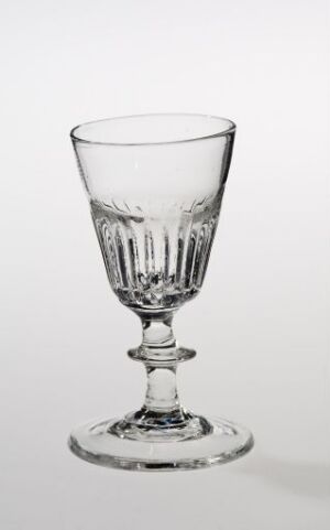  An empty, clear glass goblet with decorative vertical ridges on the bowl, a detailed stem, and a stable circular foot, set against a plain white background.