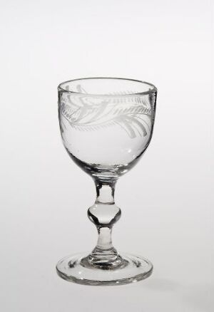  A clear glass goblet with intricate etchings stands against a gradient background, transitioning from white to gray.