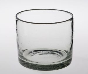  An empty, clear glass with a thickened rim stands against a white background, exemplifying simplicity and functionality in its design.