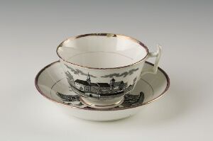  A porcelain teacup with a grayscale cityscape design and gold trim on the rim, accompanied by a matching saucer with the same design and trim, placed against a light grey backdrop.