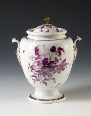  An ornate white porcelain urn with purple floral patterns and gold trim, featuring curved handles and a round, decorative lid handle.