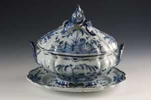  An antique-style white and blue porcelain tureen with a lid on a matching underplate, decorated with intricate cobalt blue floral motifs and designs.