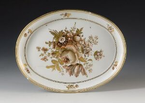  Oval-shaped ceramic plate with a detailed floral design in the center featuring creamy blooms and green foliage, surrounded by a golden-trimmed edge against a white background. Artist name and title unknown.