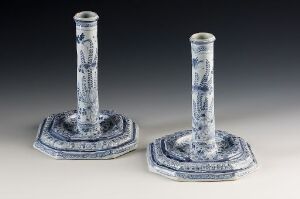  A pair of patterned blue and white ceramic or porcelain candlesticks with octagonal bases, featuring intricate floral designs, displayed against a neutral background. Artist name and title are unknown.