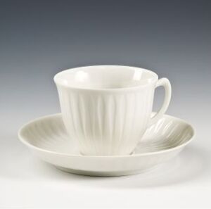  An elegant feldspar porcelain cup and saucer set by Konrad Galaaen, featuring a gleaming white finish and vertical relief decorations that provide texture to the simple, yet sophisticated design.