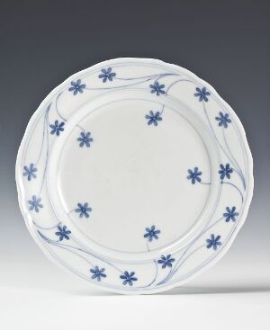  A "Facon Meissen" porcelain plate by Gerhard Munthe, featuring a creamy white background with hand-painted, dark blue floral designs and sinuous lines around the rim.