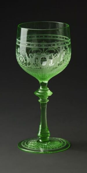  An elegant green glass goblet with intricate etched designs, displayed against a dark background, highlighting the craftsmanship and vibrant green hue of the glassware. Artist name and title are unknown.