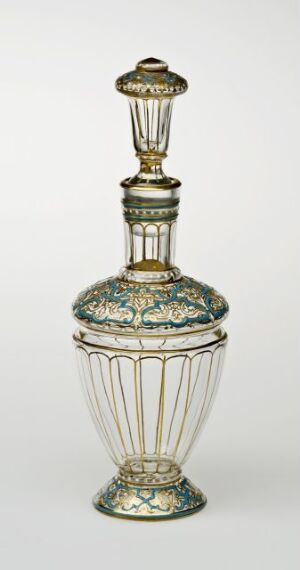  An elongated, ornate glass perfume bottle with intricate gold and turquoise embellishments on a white glass background, featuring a ribbed center section, decorative bands, and a detailed stopper.