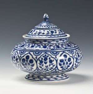  An intricately patterned blue and white ceramic lidded pot with oriental-style decorations, featuring florals and symmetrical bands. The pot has a globular base and a domed lid topped with a small knob.