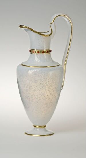  An elegant off-white pitcher with gold accents on the rim, neck, and base, featuring a speckled texture, displayed against a light gray background.