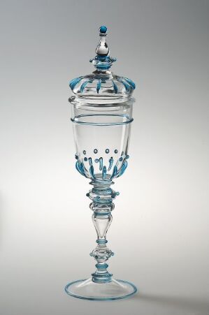  An ornate glass stemware or covered goblet with a clear body and delicate blue accents, featuring a twisted stem and a lid with a finial, set against a soft gray background.