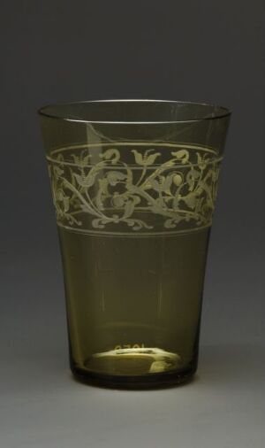  An antique smoky amber glass with an engraved foliage pattern, glowing warmly against a neutral dark gray to black gradient background.