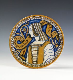  A decorative plate with a female profile in blues, whites, and golds, featuring intricate border designs and unreadable text, against a light gray background.