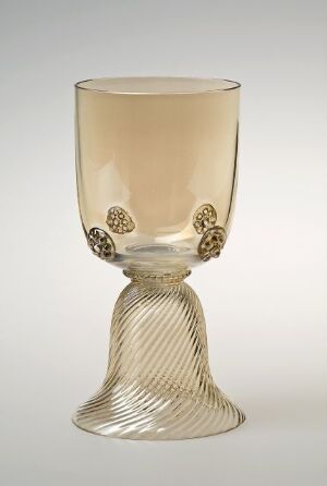  A delicate, pale amber-colored glass goblet with intricately designed gold-toned medallions around the bowl and a twisted stem, set against a light background.