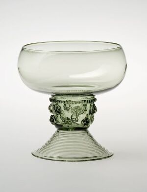  An elegant glassware piece with a large, clear bowl and a highly ornate forest green stem with leaf-like decorations, positioned against a light gray background.