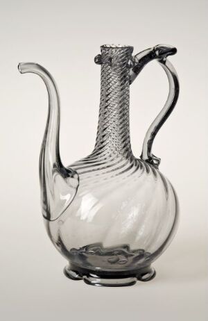  A clear glass pitcher with a twisted handle and ridged body, displaying a wavy rim, against a plain background. The craftsmanship showcases elegance through its use of transparency and texture. Artist name and title are unknown.