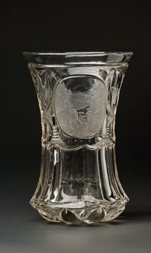  A clear glass vase with intricate cut glass patterns and an engraved cameo on a dark background.