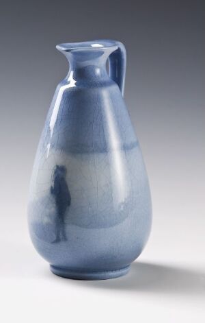  A ceramic pitcher with an ombre blue glaze, transitioning from dark at the top to light at the base, featuring a silhouette of a person in a lighter shade of blue on one side. Artist name and title are unknown.