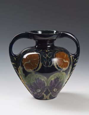  An art nouveau-style vase with a glossy black finish, featuring purple and green iris flower designs and amber-colored circular medallions, all accented with gold outlines, set against a light gray background.