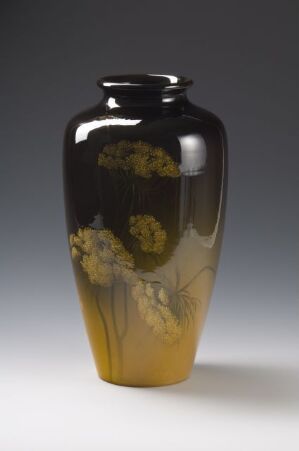  An elongated vase with a gradient color scheme transitioning from smoky transparent to dark, resembling obsidian, and then to warm golden at the bottom, adorned with delicate yellow and green floral motifs.