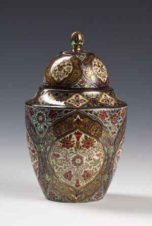  An ornate octagonal lidded container with detailed floral and geometric patterns in burgundy, green, blue, and yellow, accented with metallic gold, displayed against a soft grey background.