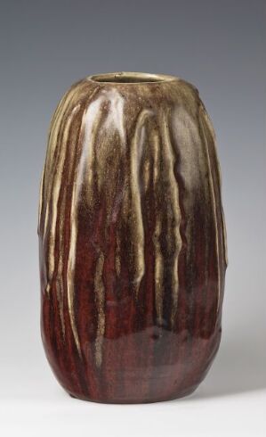  A tall, earthy brown vase with vertical creamy tan streaks against a uniform grey background. The vase has a glossy finish and tapers slightly at the top.