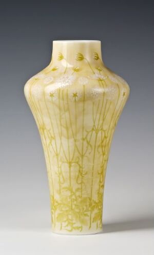  "Vase de Castigny" by Sèvres, a porcelain vase with a soft pastel yellow background, adorned with vertical golden lines and stylized floral motifs. The vase has an elongated octagonal shape with a slender neck and slightly flared mouth, exhibiting the refined elegance of Sèvres porcelain craftsmanship.