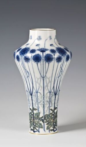  An elegantly shaped porcelain vase with hand-painted blue blooms and green stems on a white background, made by Sèvres. The vase tapers towards the neck and flares slightly at the top.