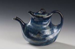  A ceramic teapot with a glossy, swirling blue and white glaze, featuring a short curved spout and a comfortably arching handle.