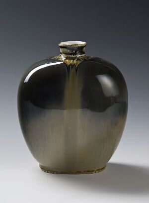  An elegant vase with a flattened spherical shape, featuring a gradient from a shiny golden color at the top to a deep black at the bottom, set against a light gray background.