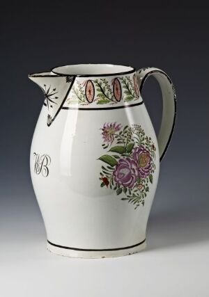  An elegant, antique-style white ceramic pitcher with hand-painted pink and purple flowers around a dark monogrammed initial, adorned with a patterned geometric design near the spout.