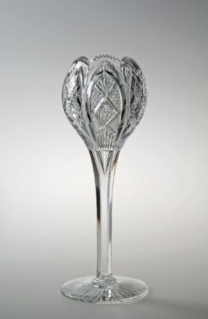  A decorative crystal glass tulip-themed object titled "Tulipan C" crafted by Hadeland Glassverk, displaying an intricate cut pattern on the tulip-shaped top with a smooth stem and flat base.