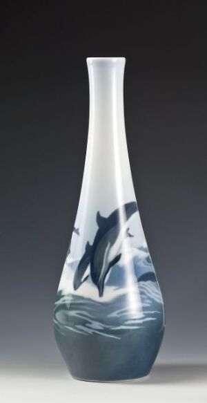  An elongated, tapered vase with a white to deep blue gradient, artistically adorned with leaping dolphins against a neutral background. Artist name and title are unknown.