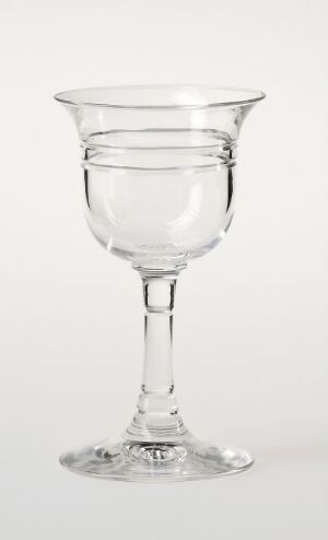  A clear glass goblet with an elegant design, featuring a stem and a two-part bowl design that resembles an inner sphere within an outer part, stands against a light background.