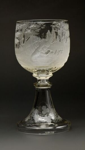  A translucent goblet with intricate etchings on the bowl, an ornate stem, and a sturdy base, displayed against a dark background, showcasing its craftsmanship and elegant design. Artist name and title are unknown.