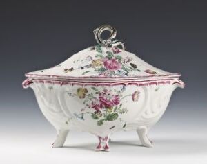  An ornately designed porcelain tureen with a lid, featuring embossed designs and painted floral decorations in shades of pink, magenta, and green, set against a soft gray background.